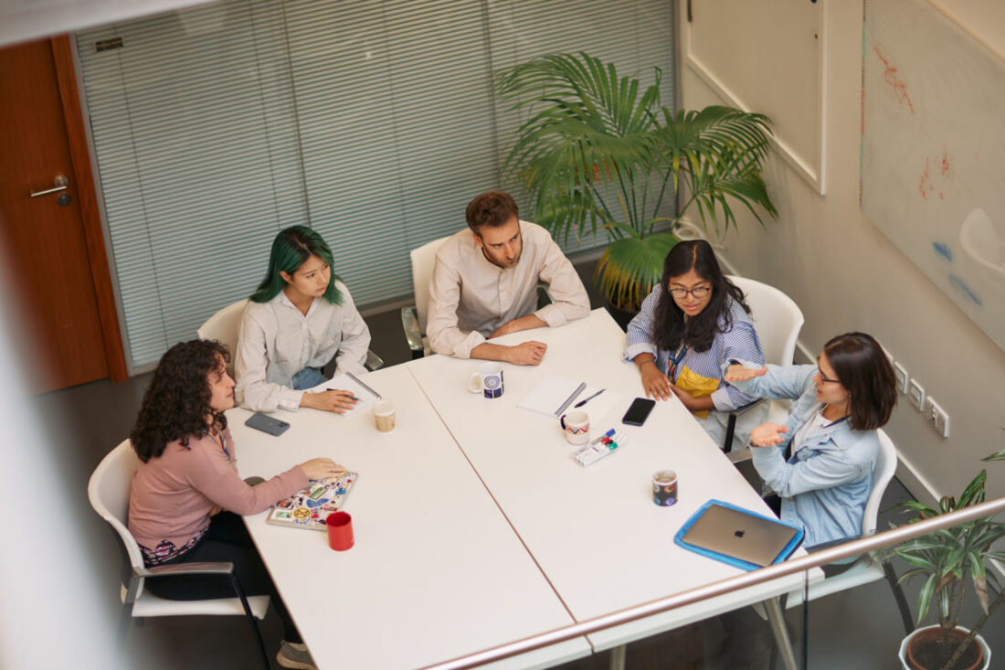 group of researchers discuss around a table and by a white board