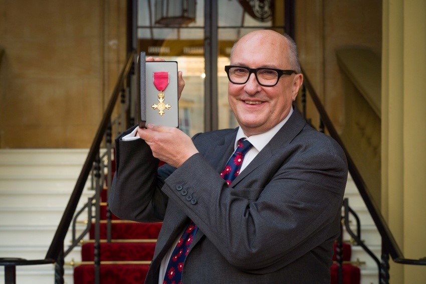 Photograph of Roger Highfield holding his OBE