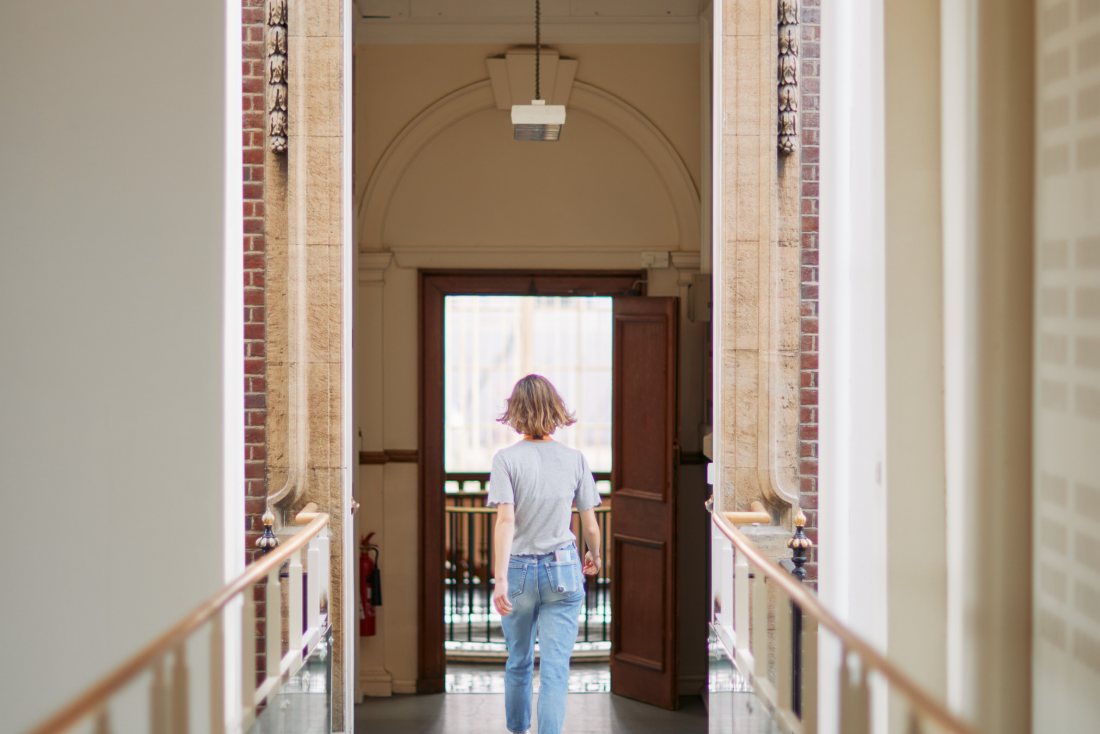 View of a person walking down the bridge into the old building of the Dunn School